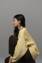 Load image into Gallery viewer, A woman in profile wearing a pale yellow knit sweater with a scalloped neckline and dark brown pants, posed against a solid gray studio background wearing WAIWAI FAN earrings, upcycled leather, espresso gold and cream, pair