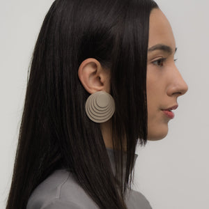 A pair of taupe layered leather earrings with concentric circular designs, handcrafted for a bold and dimensional look.