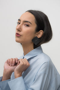 Square black leather earrings with rounded corners, featuring layered leather design for a dimensional and sculptural look.