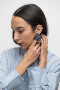 Square black leather earrings with rounded corners, featuring layered leather design for a dimensional and sculptural look.