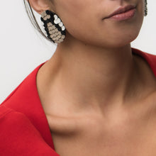 Load image into Gallery viewer, Close-up of snake-inspired earrings made from black, beige, and white leather. The layered design resembles scales, featuring a bold mosaic pattern with a textured, modern look. Handcrafted from upcycled leather, they are lightweight and sustainable.