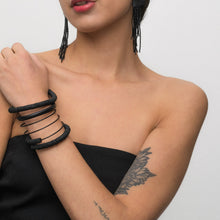 Load image into Gallery viewer, A bold, handcrafted bracelet made with individually hand-punched black leather discs, a sleek hand-stitched leather tube, and delicate black glass beads. The layered, wraparound design creates a modern and textured statement piece.