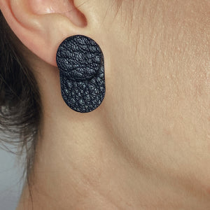 A person wearing the upcycled leather earrings with the black side of the double-sided second part facing forward for a bold and edgy style.