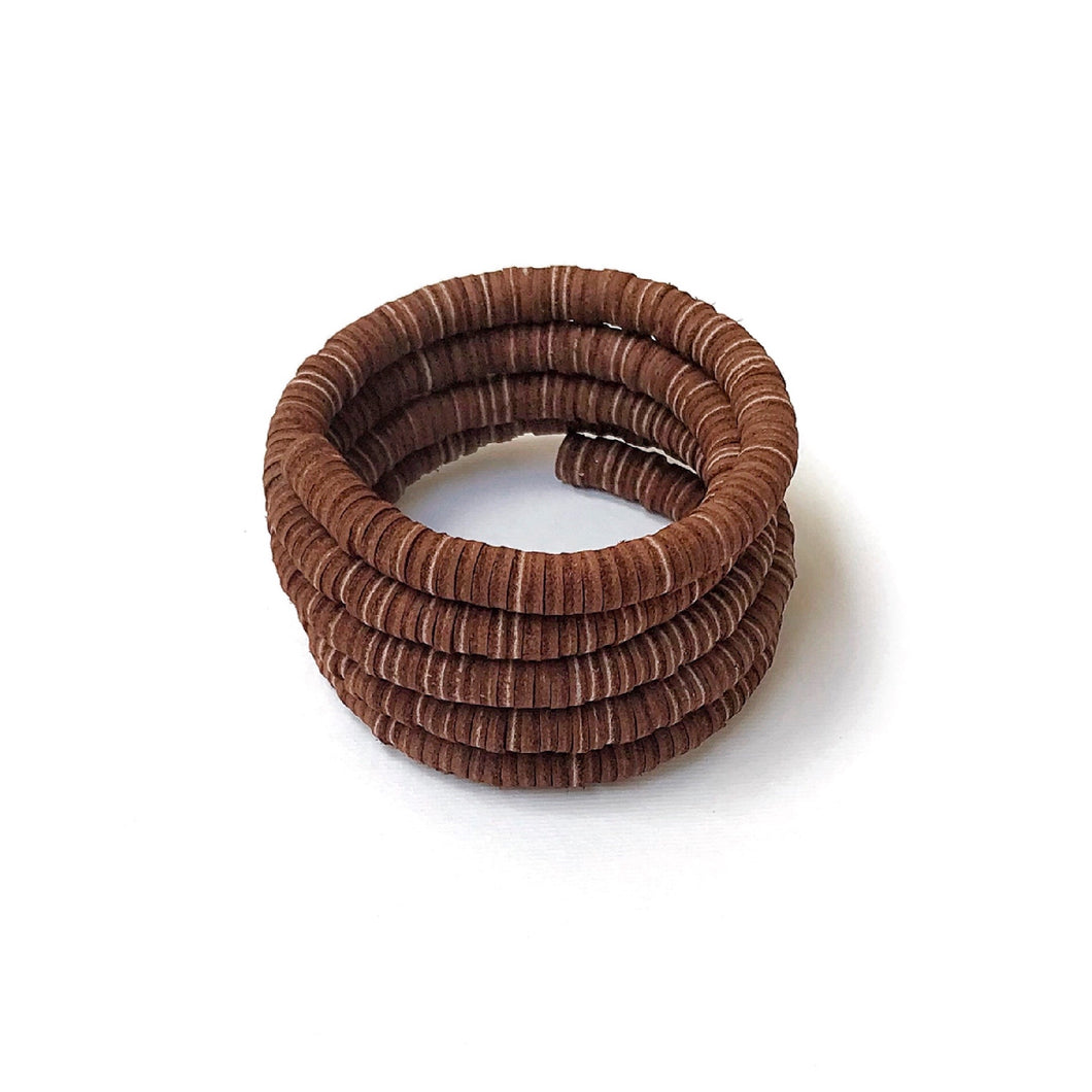 Make a statement with this helical leather cuff bracelet. Its bold simplicity and high texture are inspired by the natural world and the resilience it embodies. Crafted from individually punched genuine leather sequins, this cuff is soft, lightweight, and comfortable for all-day wear. The stainless steel memory wire allows for easy adjustment to fit any wrist size. Add a touch of nature-inspired elegance to your everyday look.